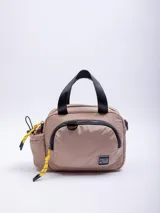 Bolso tipo conservadora de temperatura, color beige/nude, con asas superiores negras y correa ajustable desmontable negra. Presenta un bolsillo frontal con cierre negro y un bolsillo lateral para botella con cordón elástico amarillo y negro. Tiene un parche cuadrado negro con texto blanco en el frente.