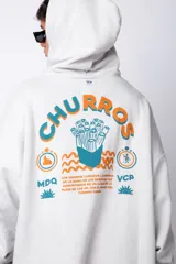 Buzo canguro oversize de algodón rústico, color gris claro, con capucha y cordones ajustables con logo estampado. Presenta un diseño gráfico pequeño en el pecho y detalles estampados en la manga.