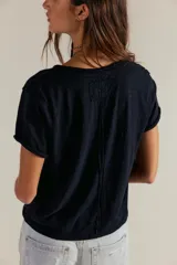 Remera de jersey suave color negro, de calce relajado, corte recto y largo corto, con escote en V y mangas cortas caídas con puño fijado.