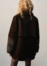Abrigo de efecto pelo en color marrón, con diseño recto, cuello camisero, manga larga y cierre delantero con botones. Cuenta con forro interior.