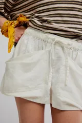 Short corto color blanco de mezcla de lino y algodón, con calce relajado, cintura con cordón ajustable y grandes bolsillos delanteros envolventes.