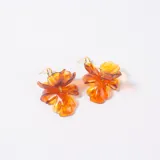 Caravanas con diseño de flor en resina traslúcida color ámbar, con gancho metálico dorado.