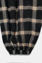 Pantalón bombacho de tiro medio con cintura elástica ajustable con cordones, bolsillos laterales ocultos en costura y bajo abullonado acabado en elástico. Estampado a cuadros en tonos beige y negro.