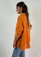 Camisa color salmón de lino, de corte recto, con cuello clásico, cierre frontal con botones y mangas 3/4 con trabilla.