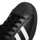 Championes Adidas modelo Superstar ADV, de diseño clásico con exterior de cuero negro, las icónicas tres tiras laterales en blanco y la característica puntera de goma. Incluye el logo Superstar en dorado en el lateral y el logo de la marca en la lengüeta y el talón.