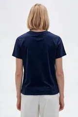 Remera de manga corta de algodón en color blanco, con cuello redondo y diseño holgado. Presenta un estampado frontal con detalle de acabado metálico (foil).