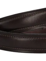 Cinturón de hombre confeccionado en cuero natural, con acabado liso y lustrado. Presenta pespuntes decorativos a tono y una hebilla metálica en color plata envejecida.