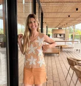 Chaleco de cuero tostado en el frente con apliques de grandes flores de crochet blancas, y espalda de tejido de punto de algodón. Presenta cuello redondo y diseño sin mangas.