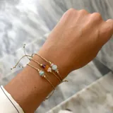 Set de tres pulseras ajustables con hilo encerado dorado y cuentas de piedras naturales, incluyendo amazonita, cuarzo rosa, ámbar, amatista, piedra luna y larimar.