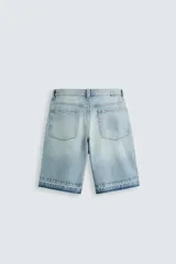 Bermuda de denim de algodón, color negro lavado, de corte ancho (baggy fit) y tiro medio. Presenta cinco bolsillos y bajo con acabado irregular deshilachado.