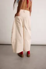 Pantalón de gabardina de algodón color marfil, de silueta tipo barrel con pinzas delanteras, tiro alto y diseño holgado con costuras decorativas.