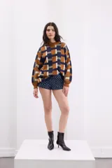 Sweater de punto con diseño geométrico de cuadros en tonos azul, ocre y gris. Presenta cuello redondo, mangas largas y un corte holgado.