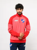 Buzo deportivo de medio cierre marca Umbro del Club Nacional de Football. Presenta un diseño en tonos azul y gris jaspeado, con cuello alto, mangas largas y detalles de costuras en contraste. Incluye el escudo del club y logo de la marca en el pecho.
