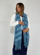 Bufanda tipo pashmina de acrílico, modal, lana y alpaca, con diseño a rayas horizontales en tonos de azul y flecos en los extremos.