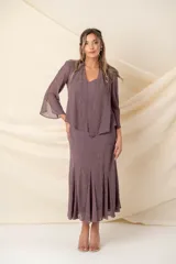Vestido midi de crepé color marrón, compuesto por un vestido solera de corte al bies con terminación en godet y una casaca a juego. Ambas piezas presentan delicados apliques de piedras al tono con diseño ornamental.