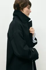 Abrigo de paño de lana con cuello alto estructurado, cierre frontal y mangas largas con detalle de botón en el puño.