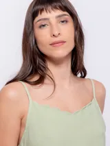 Top color durazno de breteles finos y escote con terminación ondulada.