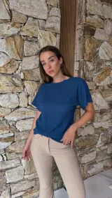 Blusa de manga corta color azul oscuro con textura arrugada o plisada, cuello redondo con borde festoneado.