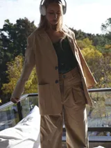 Pantalón beige de corte ancho con pinzas y bolsillos laterales.