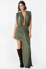 Vestido corto de diseño asimétrico en color verde oliva, con escote profundo en V, drapeado frontal y una caída lateral larga que llega hasta el suelo. Sin mangas y con ajuste entallado en la falda.