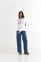 Remera de manga larga color beige con cuello redondo a la base. Presenta un estampado frontal con un dibujo de labios en color fucsia y la palabra 'BESITO' en color negro.