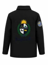 Campera impermeable de tela taslon color negro, con diseño de cuello alto y cierre frontal. Presenta un gran bordado en la espalda que incluye el escudo nacional uruguayo y el logo de la marca Bagual, además de un parche circular con la bandera de Uruguay en la manga.