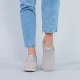 Zapatos slip on de gamuza en color gris, con suela blanca y detalle de cierre lateral funcional.