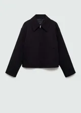Chaqueta negra de diseño oversize con cuello camisero y cierre frontal de cremallera. Cuenta con forro interior y bolsillos laterales.