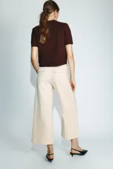 Pantalón culotte de tiro medio en color beige, con bolsillos de plastrón en el frente y costuras verticales. Incluye un cinturón trenzado fino en color marrón a contraste.