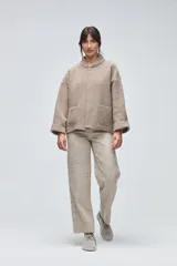 Chaqueta de lana hervida en color beige, con diseño de corte recto, cuello alto tejido, mangas largas con puños vueltos y bolsillos frontales tipo parche.