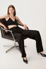 Pantalón negro de tiro alto con trabillas, bolsillos laterales y falsos bolsillos de vivo en la espalda. Incluye cinturón de lazo en el mismo tejido.