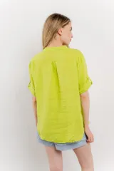 Camisa de lino color verde lima, de calce relajado, con cuello mao, botones al frente y bolsillo en el pecho. Las mangas son cortas y pueden usarse arremangadas.