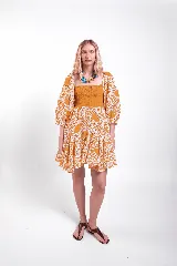 Vestido corto de encaje mostaza, con cuerpo superior fruncido y elastizado, escote recto y mangas abullonadas. Falda corta con volados y diseño amplio.