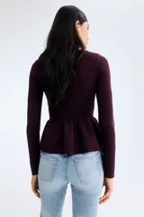 Top de punto acanalado entallado, color bordó, con escote bote, mangas largas y detalle de peplum con vuelo en la cintura.