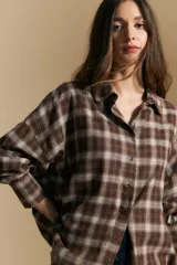 Camisa de corte oversize con estampado de cuadros en tonos marrones y beige, cuello clásico y cierre frontal con botones.