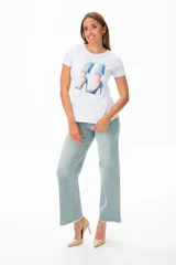 Remera blanca de algodón con estampado de piernas con jeans y zapatos de tacón azules.