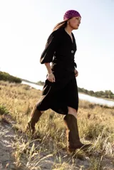 Pollera midi negra con corte evasé, cintura alta y cierre cruzado con botón.