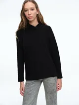 Buzo tejido de punto color negro, con capucha integrada, mangas largas y tajos laterales en el ruedo.