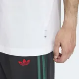 Remera de algodón blanca con cuello redondo y corte holgado. Presenta un estampado gráfico central que combina el logo de Adidas Originals con un personaje animado que viste una gorra y zapatillas.