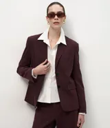 Blazer sastre de corte recto y estructura firme, color bordó con estampado de rayas de tiza. Presenta cuello con solapas definidas, cierre frontal con dos botones y mangas largas.