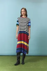 Vestido midi de algodón con diseño de rayas horizontales en color blanco y negro en el torso, mangas cortas con bloques de colores celeste, azul, verde y amarillo, y parte inferior con franjas anchas en rojo, amarillo y azul. Cuenta con cuello redondo ribeteado en rojo.