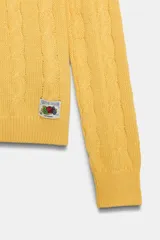 Sweater oversize de punto trenzado 100% algodón en color amarillo, con cuello redondo, manga larga y aplicación de parche gráfico Fruit of the Loom en el delantero.