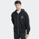 Campera tipo hoodie con cierre frontal, color negro, con capucha ajustable mediante cordones y bolsillos tipo canguro. Presenta un parche circular con el logo de la marca en el pecho.