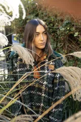Buzo canguro oversize de paño de lana gris con capucha estampada y cuello de corderito blanco. Cuenta con aberturas laterales en el ruedo y detalles de cuero sintético marrón en el cierre frontal y etiqueta.