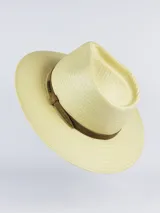 Sombrero de paja tipo australiano, color beige, con cinta marrón oscura decorativa alrededor de la copa y detalle de placa metálica con la marca.
