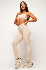 Calza deportiva de tiro alto color beige, con costuras laterales en color blanco que recorren la prenda desde la cintura hasta los tobillos.