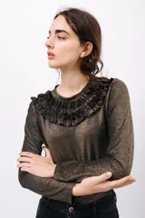 Remera de manga larga confeccionada en tejido de lurex negro con destellos dorados. Detalle de volados en el cuello tipo collar.