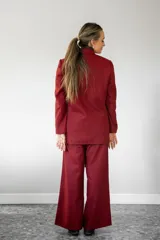 Blazer de corte sastrero con estampado cuadrillé en tonos rojos y negros, con solapas clásicas y cierre frontal. Presenta detalles de pines decorativos en las solapas.