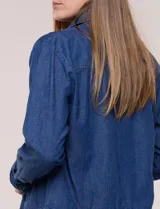 Campera de denim liviano azul, de corte clásico y silueta recta, con cuello camisero, cierre frontal con botones rústicos y bolsillos con solapa en el pecho.