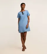 Vestido corto de color azul claro, confeccionado en liocel, con cuello redondo, mangas cortas y detalle de costura horizontal en el busto. Cuenta con bolsillos laterales.